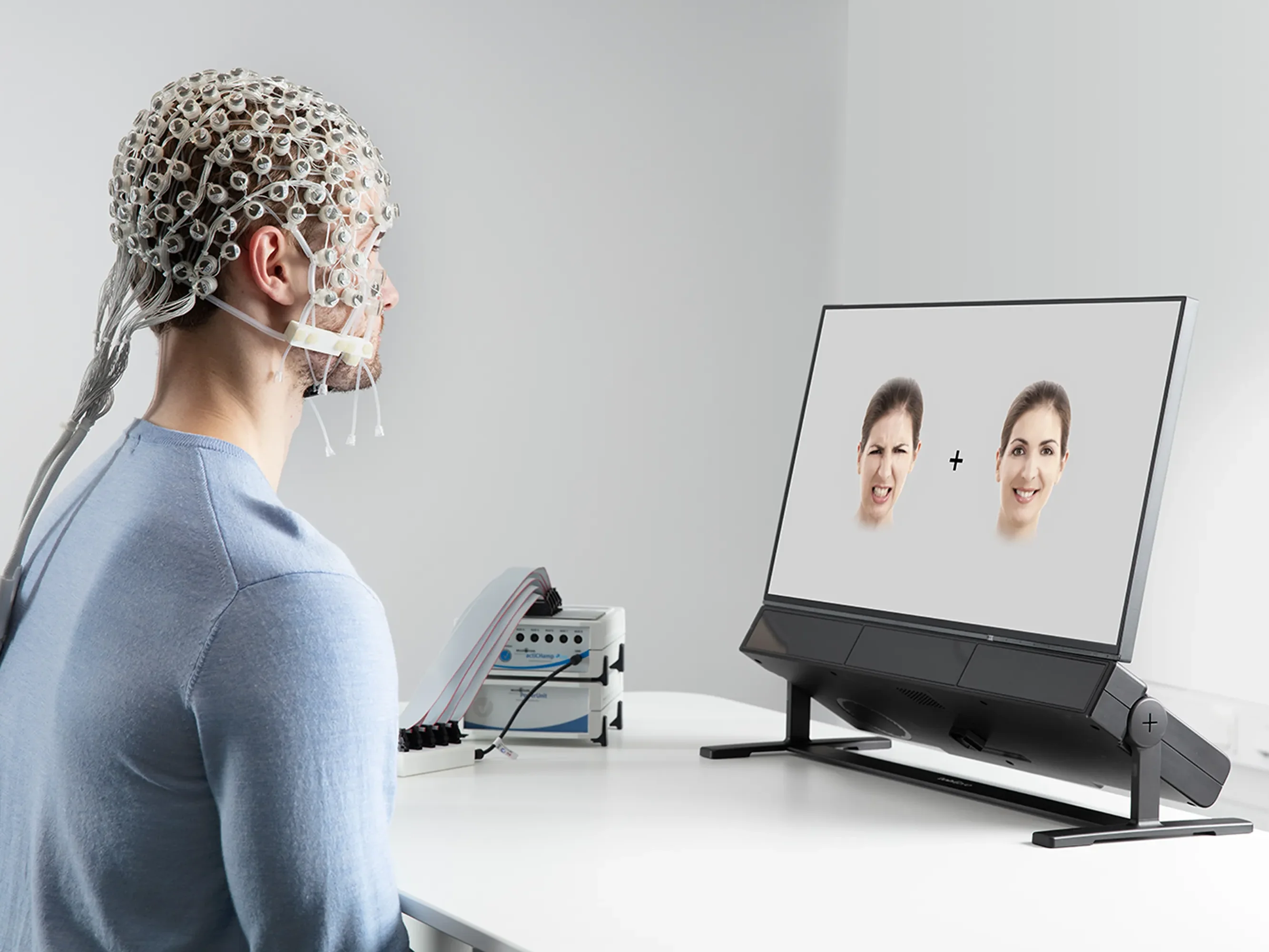Man with electrode cap, looking at a monitor.